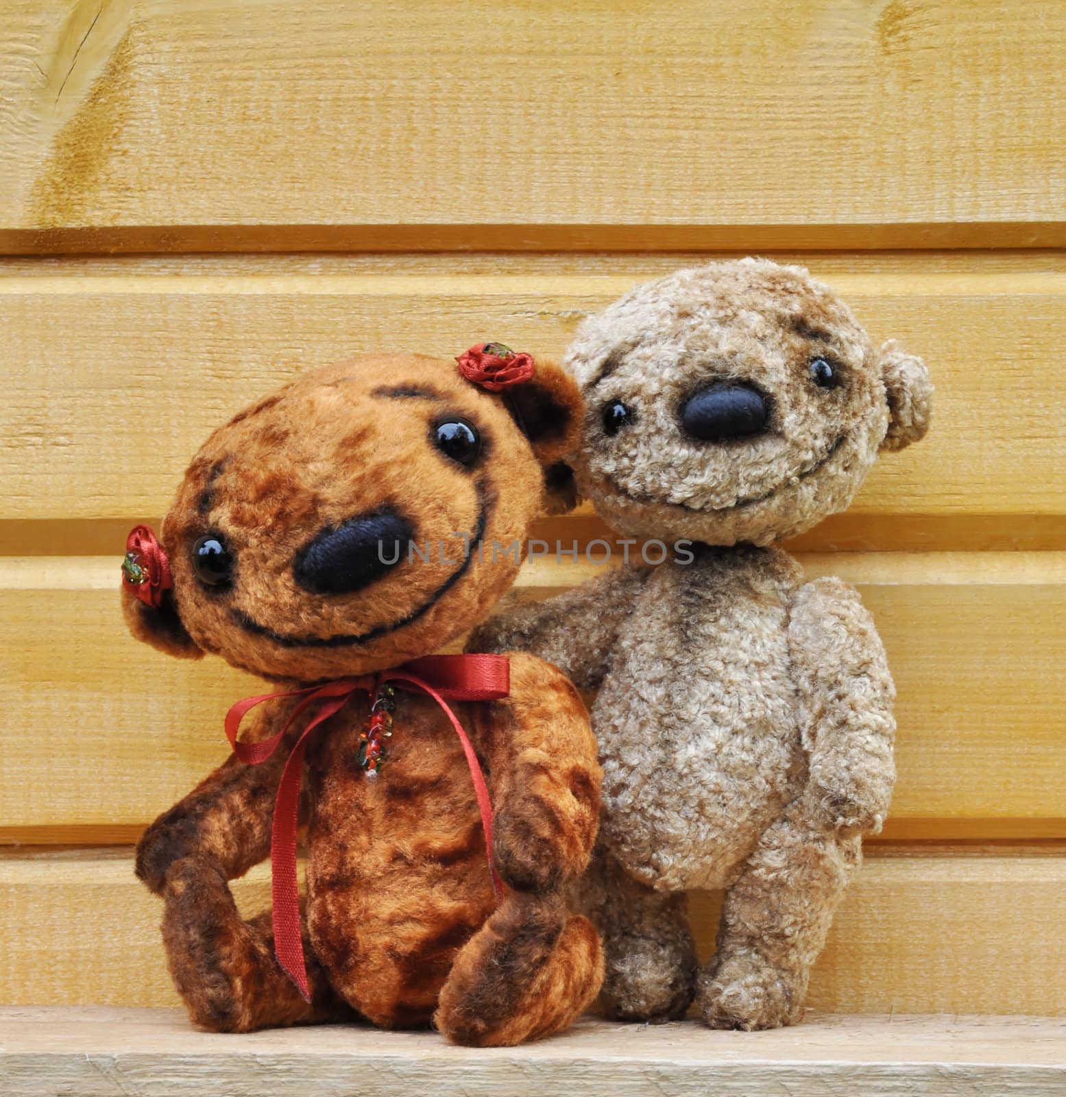 Teddy bears against a wooden wall. Handmade, the sewed plush toys