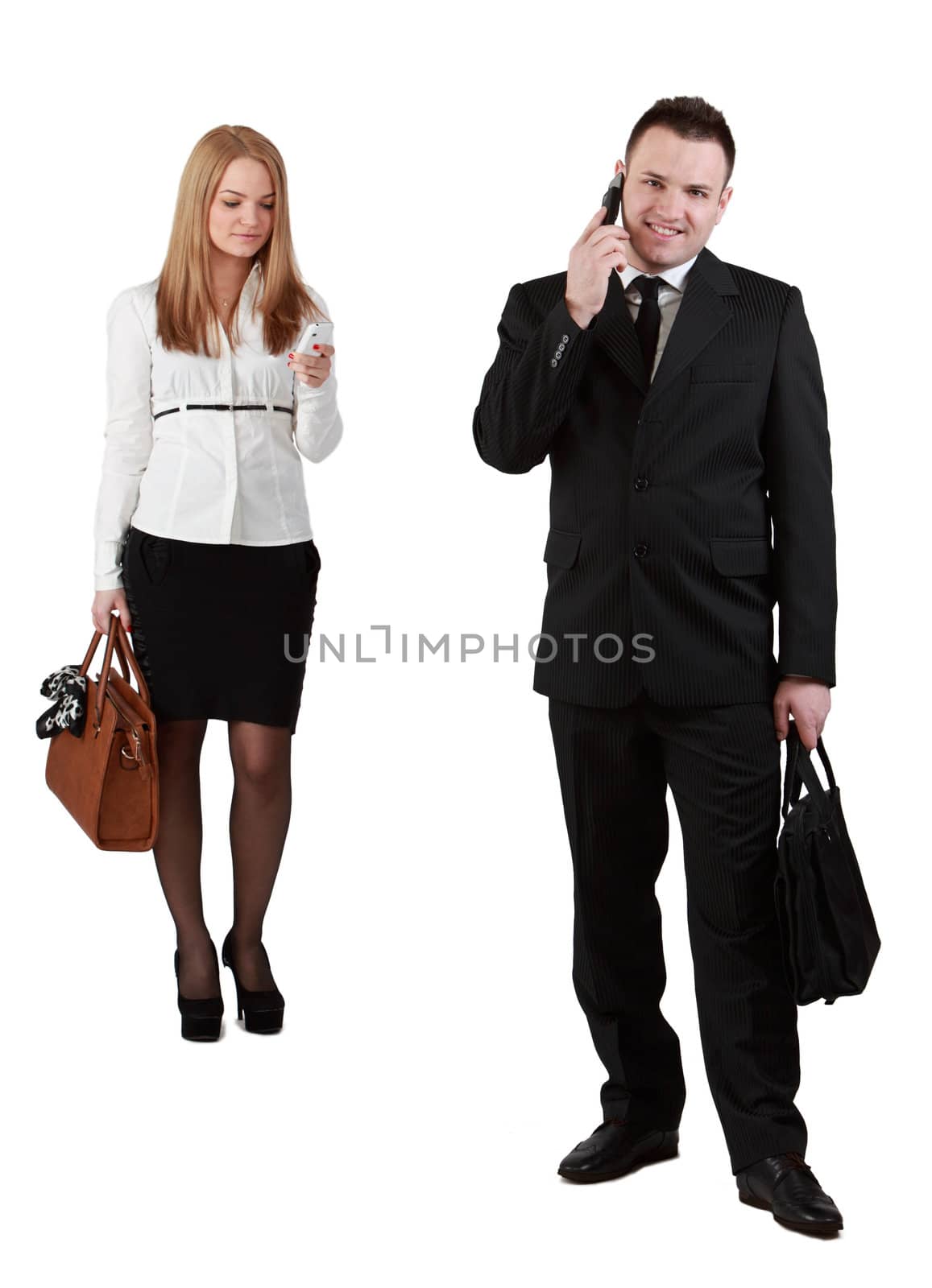 Studio shot of a young couple using mobile phones against a white background.