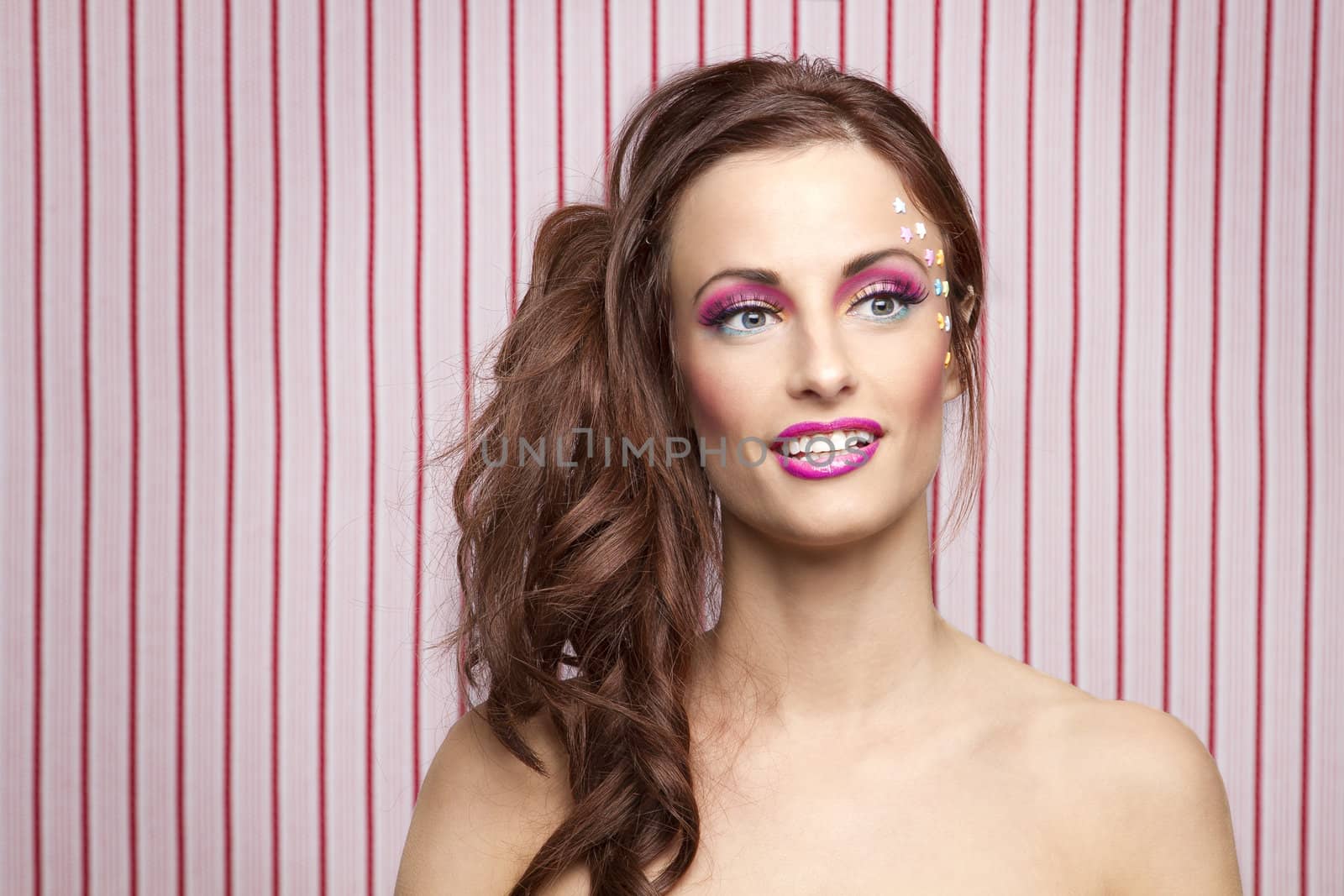 Young woman with colorful makeup and star candy glued to her face
