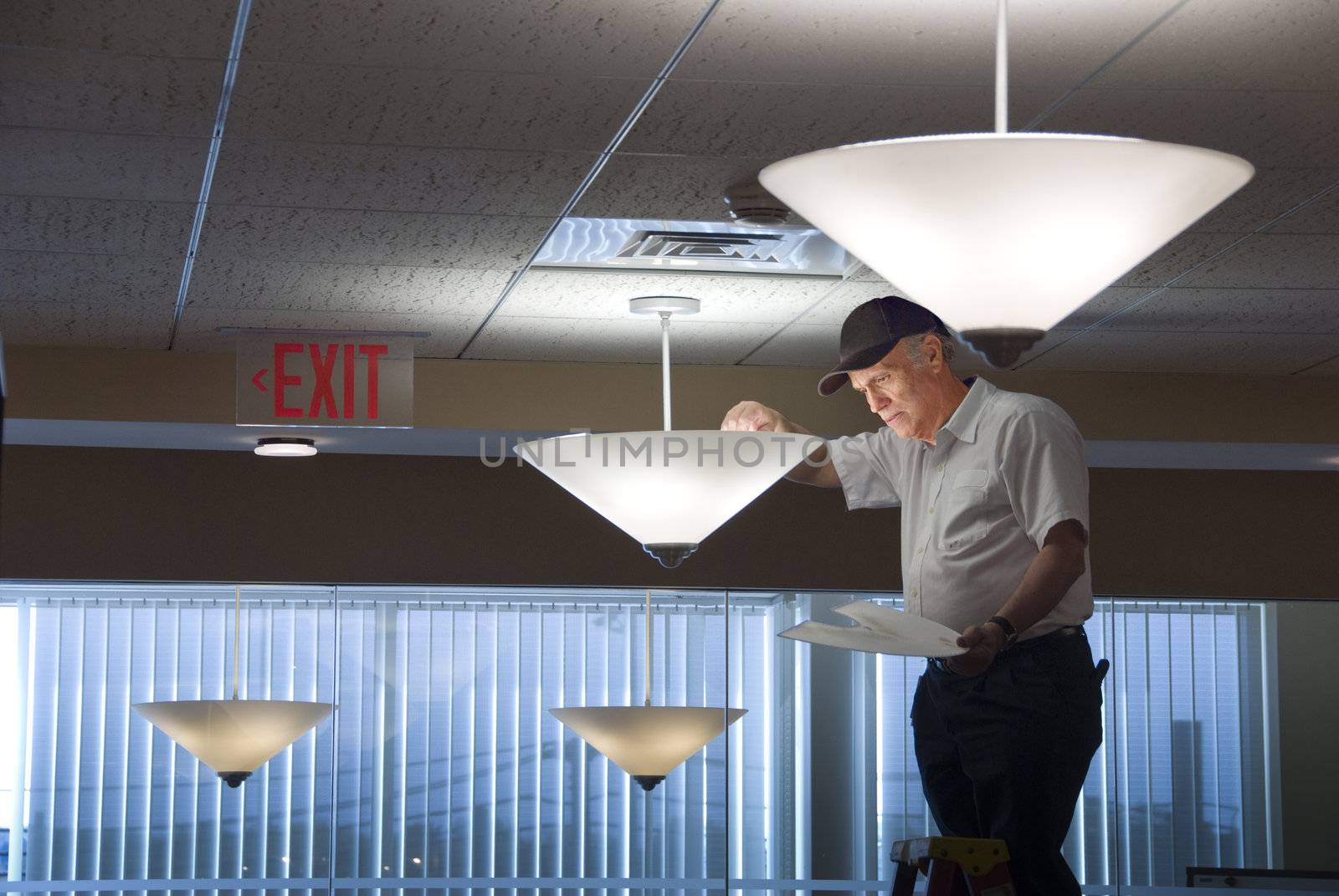 Maintenance man changing light bulbs in business office
