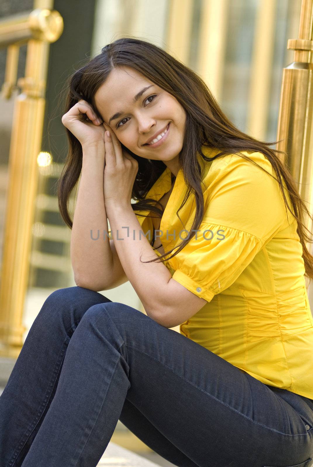 beautiful young woman in yellow blouse sits on the street