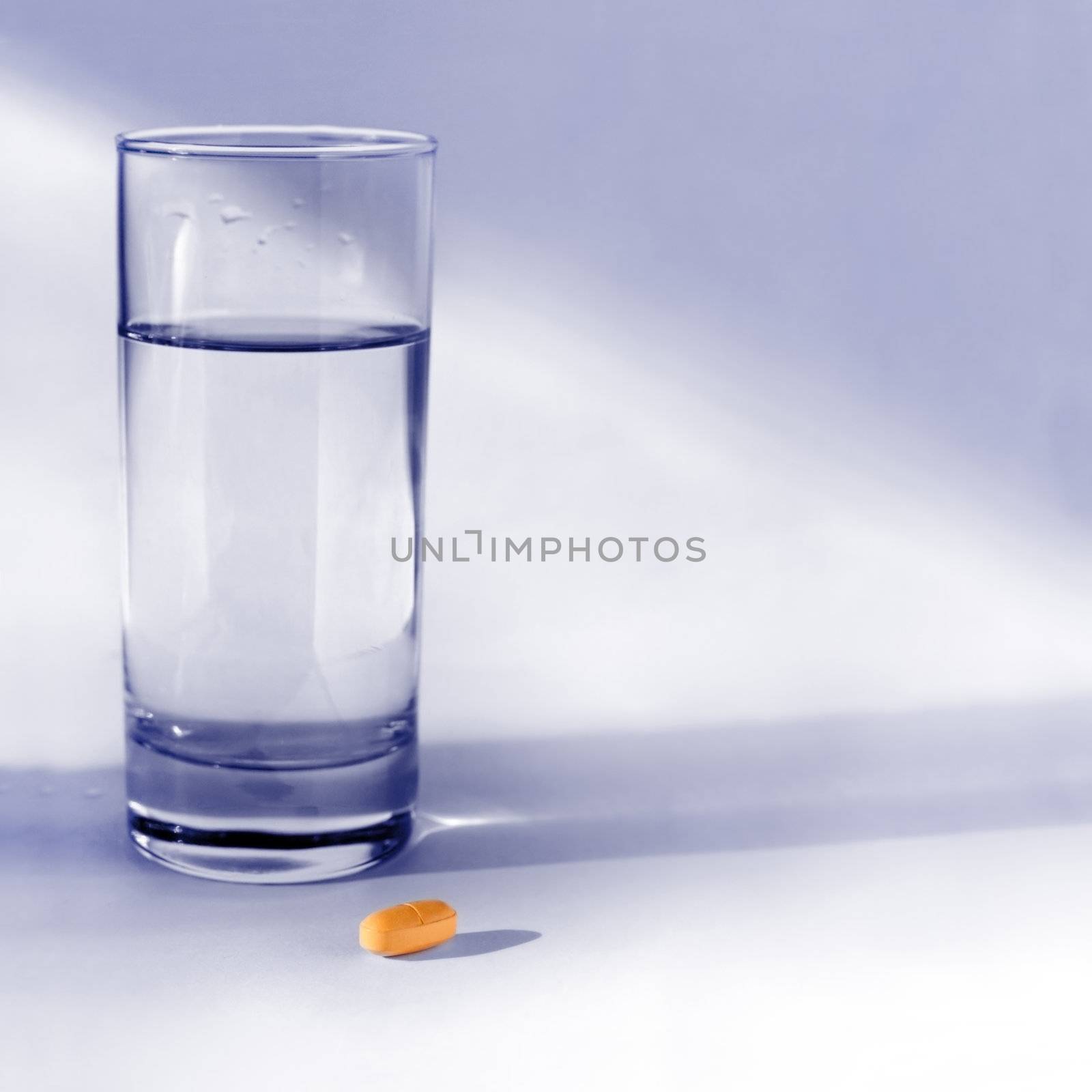 glass of water and orange tablet