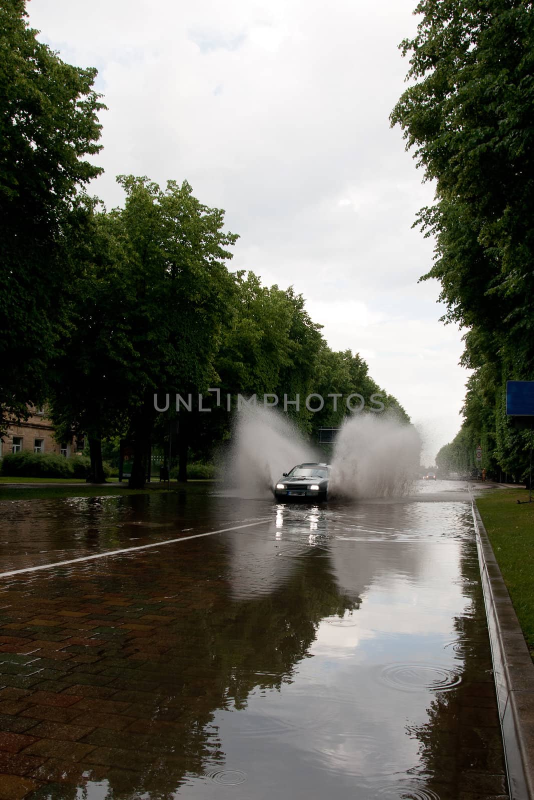 after rain flooded city street and car splashes through