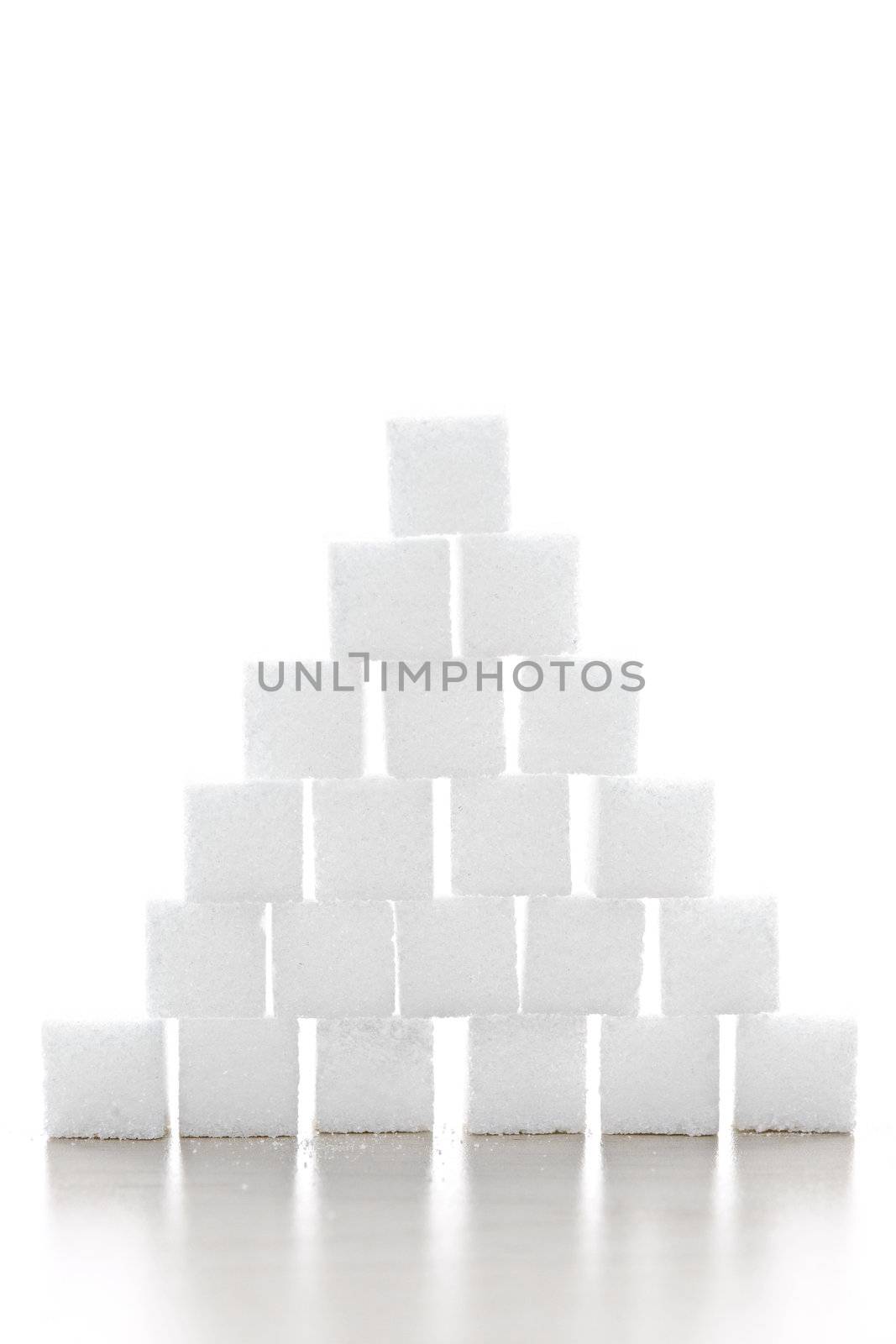 Pyramid of white sugar cubes stacked up on white background