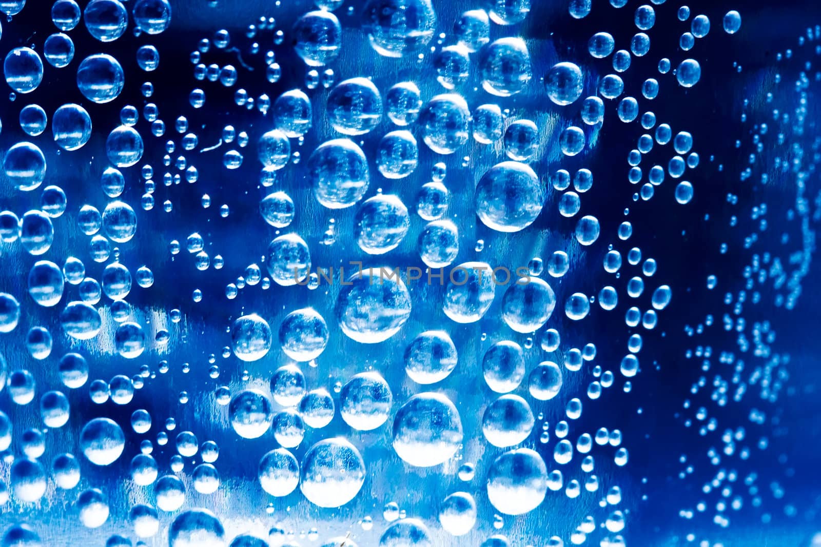 Bubbles in glass of water on a blue background