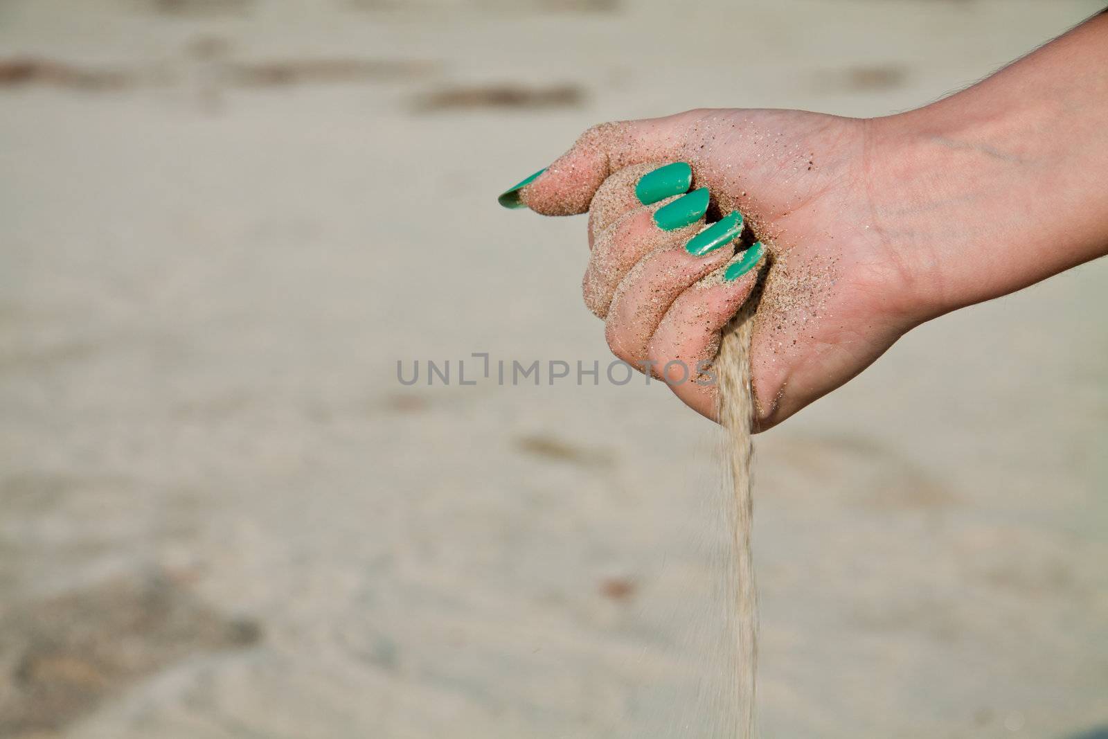 Sand flowing from a woman hand with manicure.