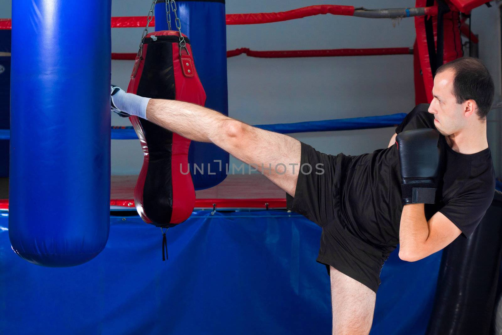 Boxer roundhouse kicking a sand bag