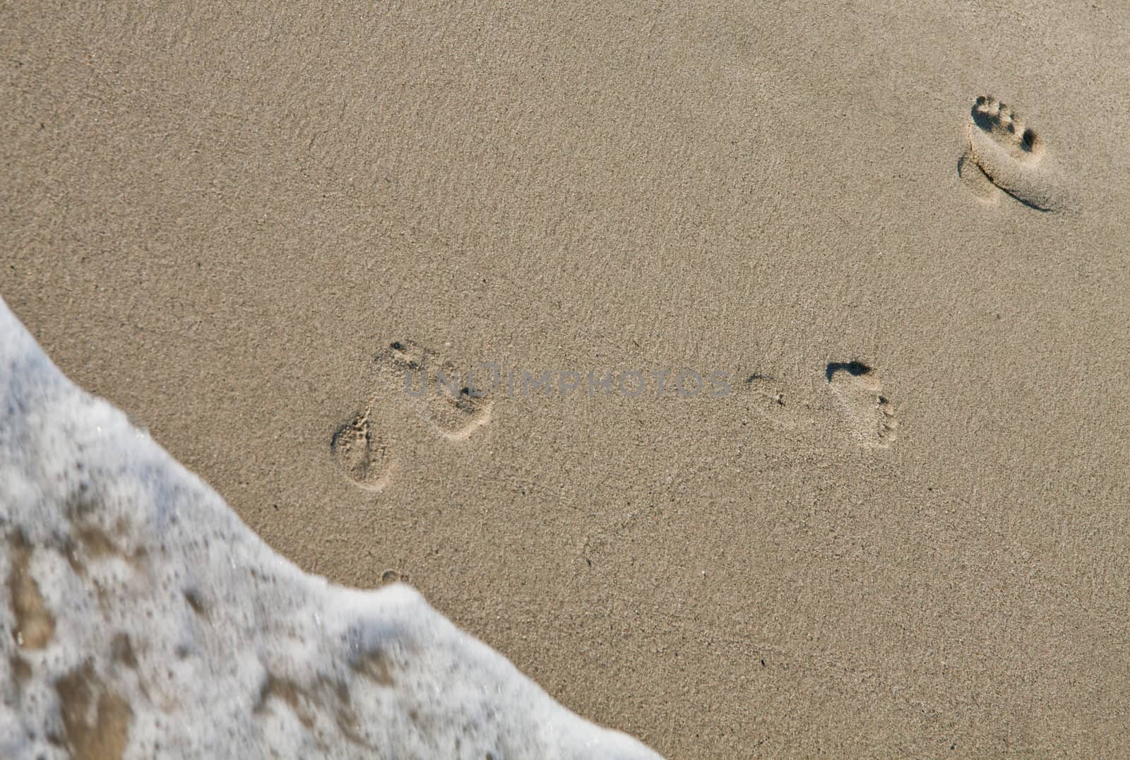 Three footsteps on the beach coming out of the water.