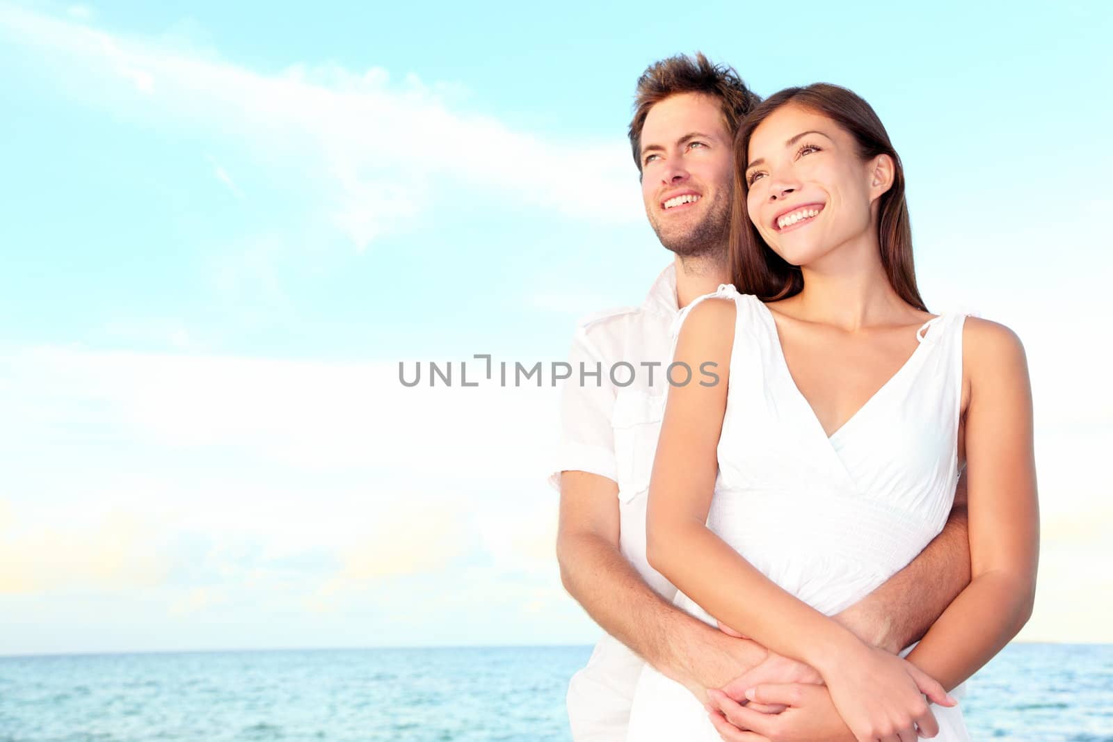Happy beach couple portrait of beautiful young romantic interracial couple smiling happy embracing on beach during summer vacation. Caucasian man, Asian woman.