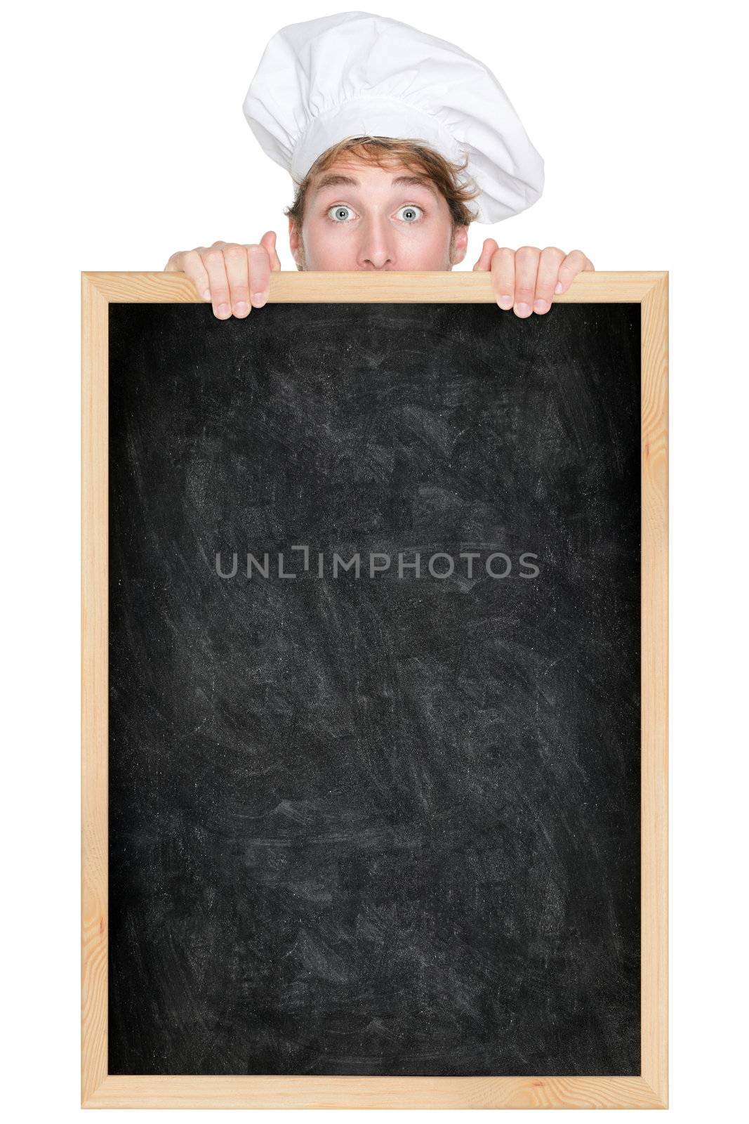 Funny chef showing blank empty blackboard menu sign for restaurant menu or recipe. Man chef cook or baker hiding behind chalkboard peeking over funny. Isolated on white background.