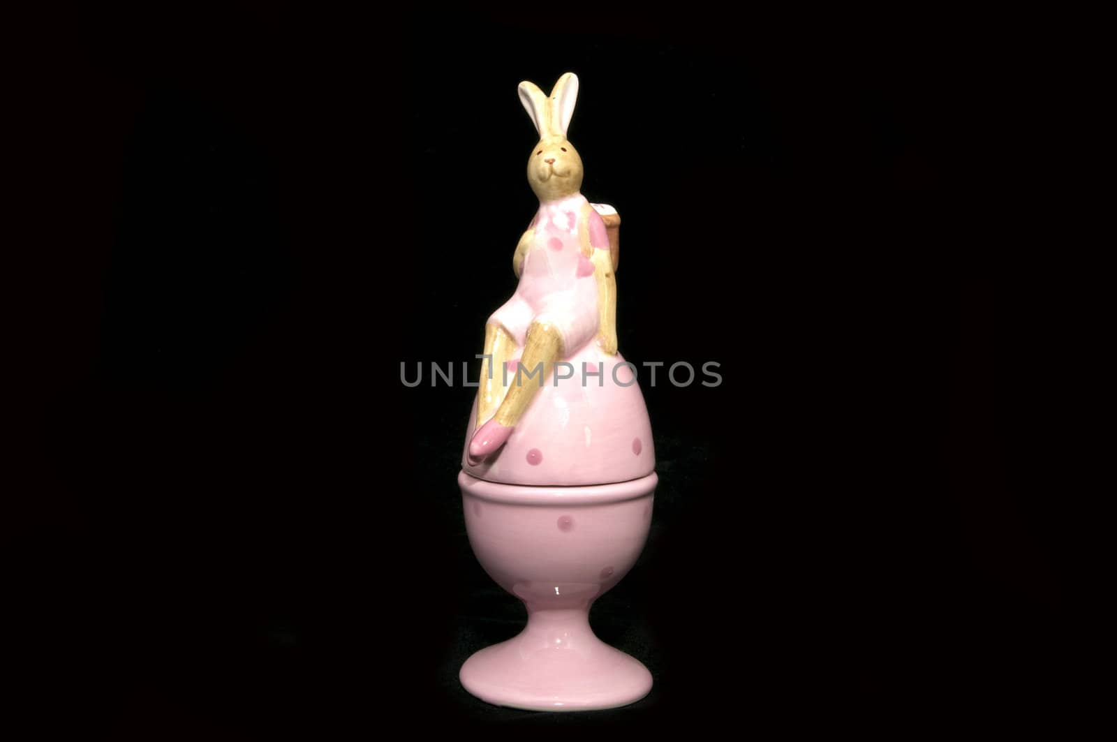 Ceramic Easter Bunny at the egg on a black background