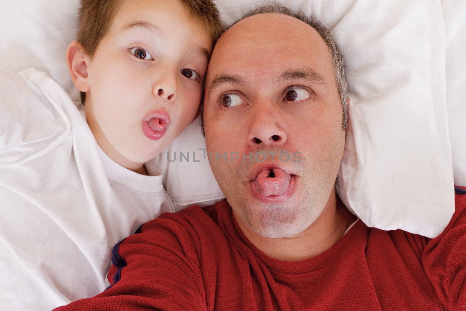 Father and son having fun in the bed by rolling their tongues.