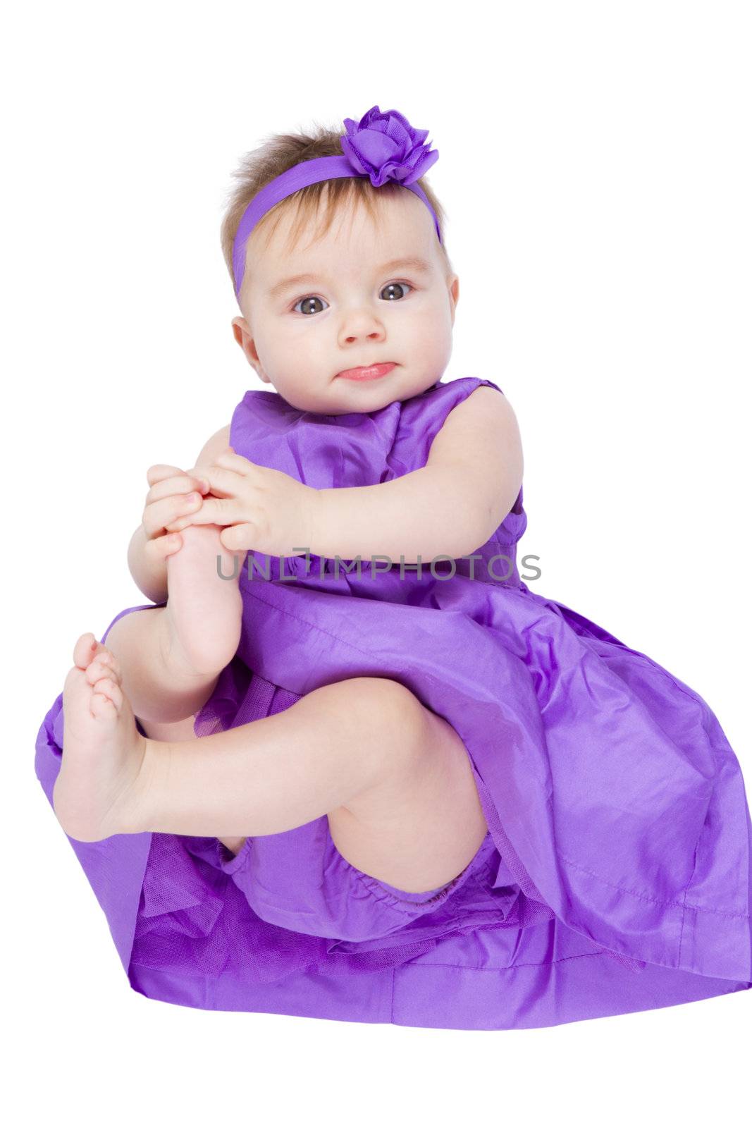 Pretty young baby girl in her purple dress and headband looking at camera.