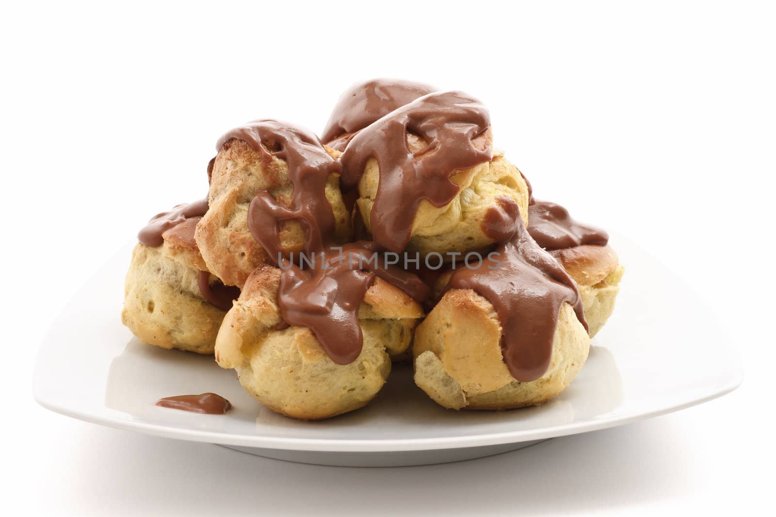 profiteroles with chocolate sauce over white background