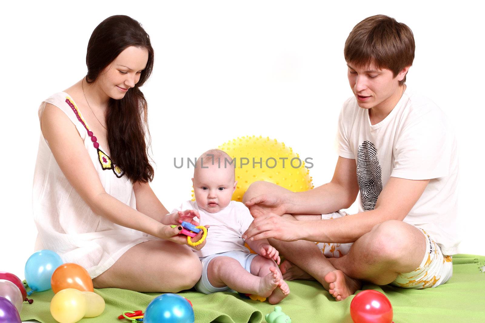 The young family, mum, the father and the son sit on a green plaid and play