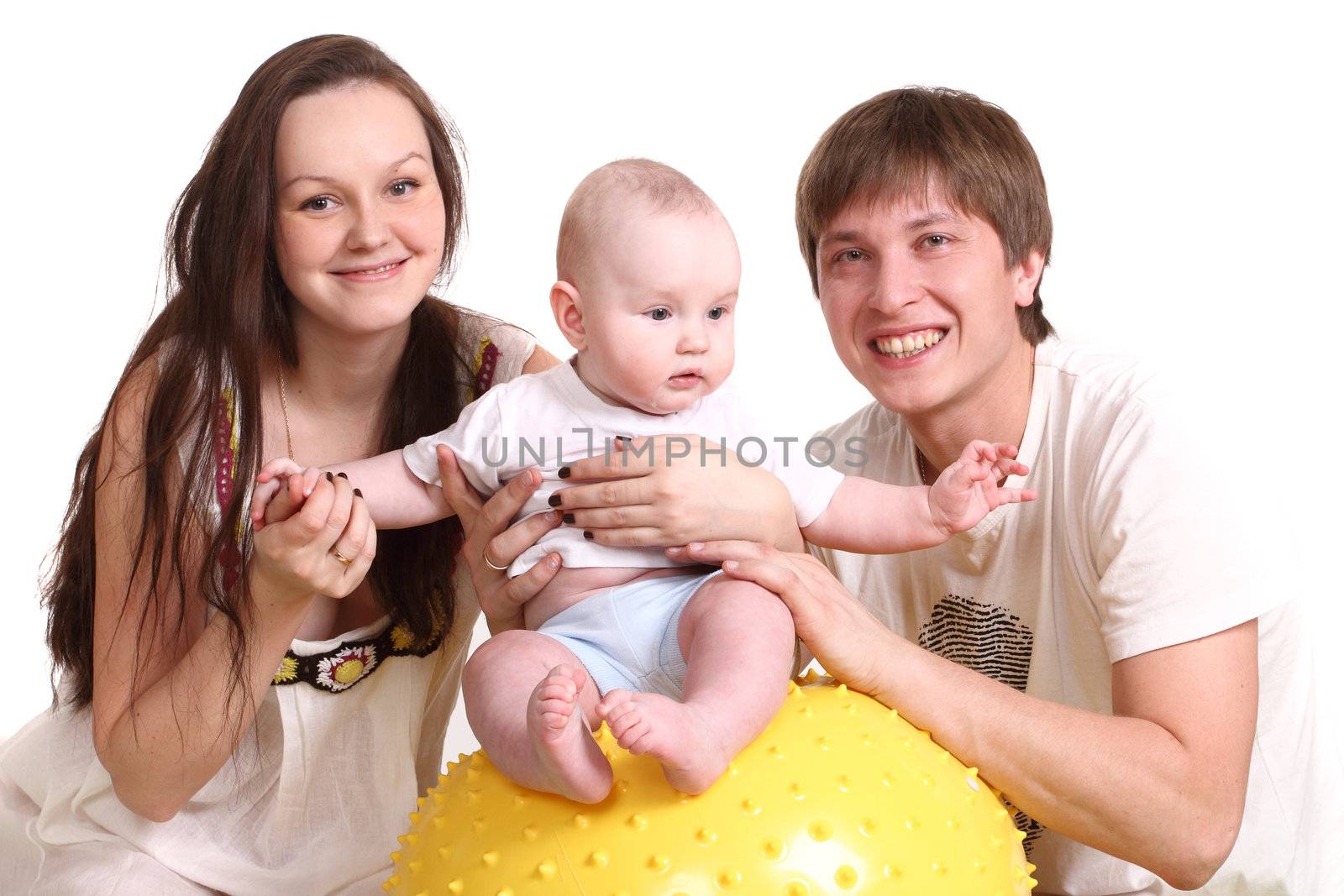 Portrait of a young family on a white background. The father, mum and the kid. A horisontal format. The kid sits on a yellow ball