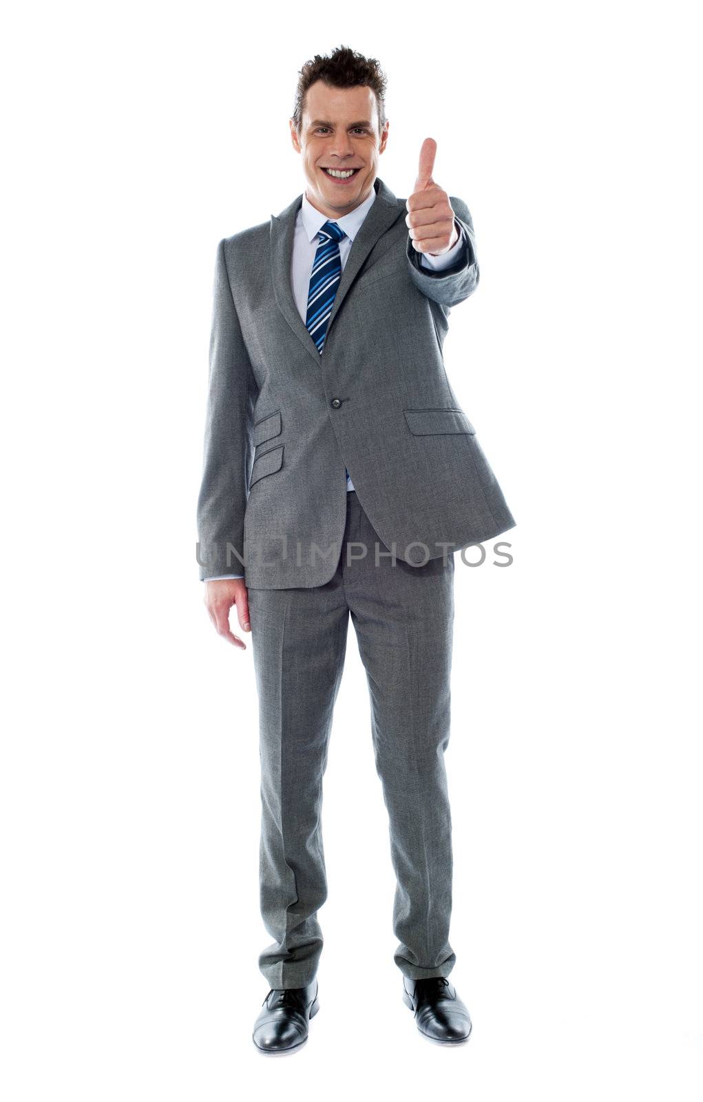 Confident businessman gesturing thumbs up by stockyimages