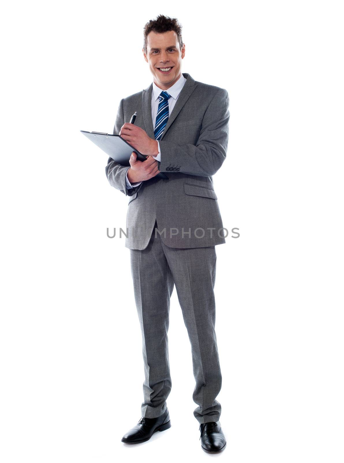 Smiling businessman writing on clipboard isolated over white