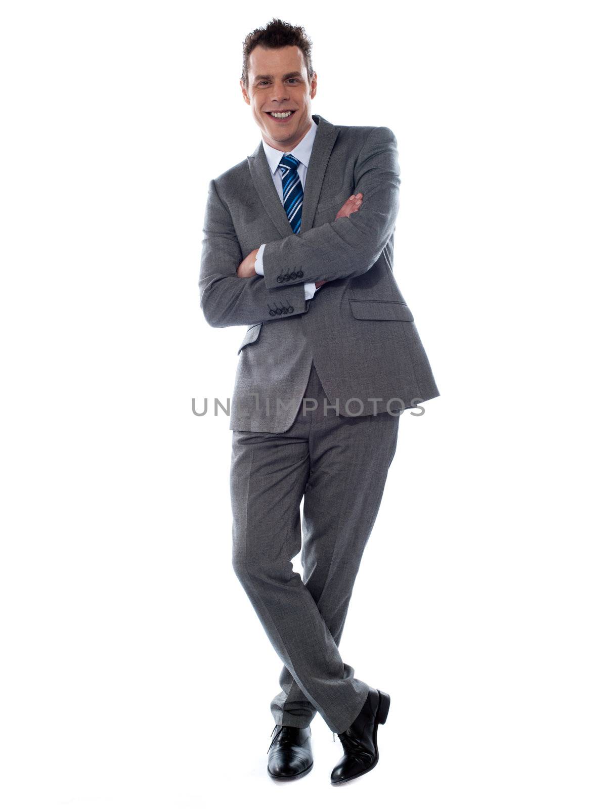 Cheerful young businessman leans against wall by stockyimages