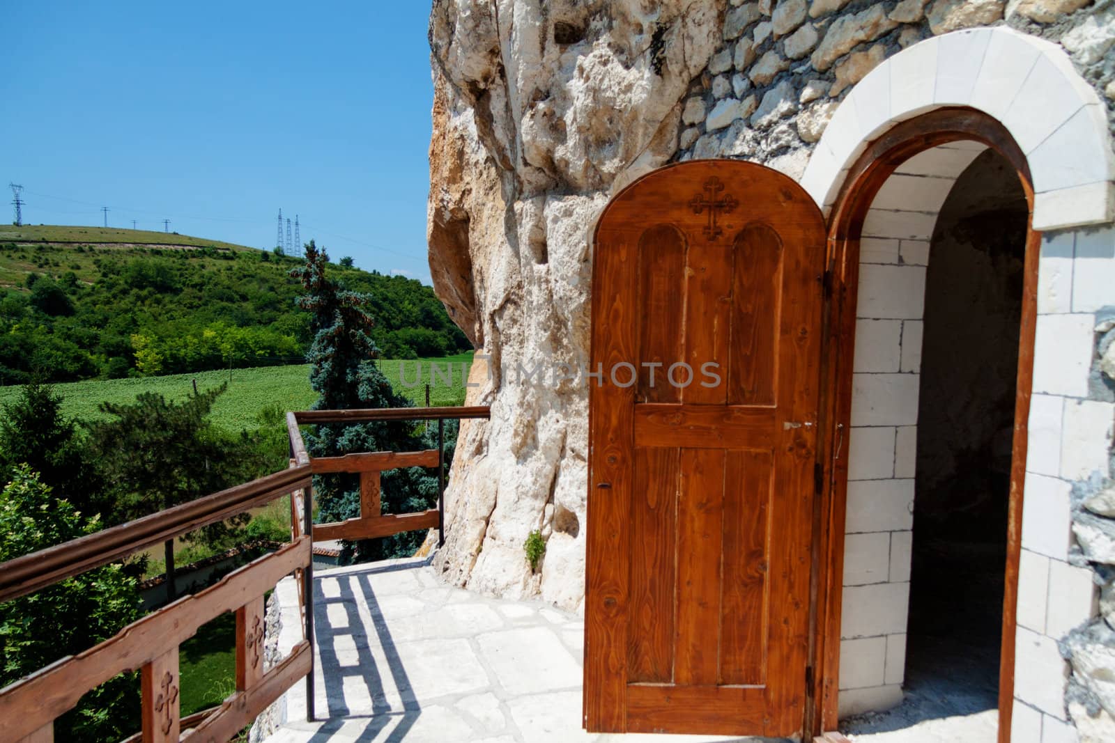 Orthodox monastery excavated in the rocks with open wooden door by Lamarinx