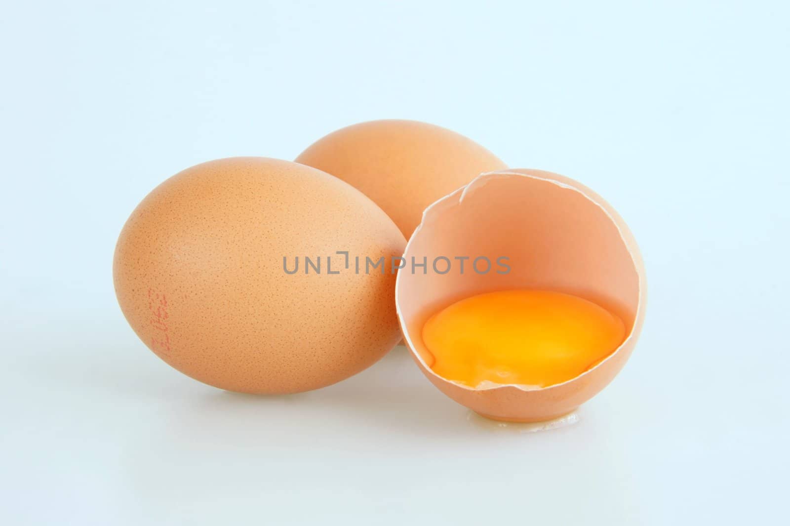 Three eggs with one broken showing the yolk