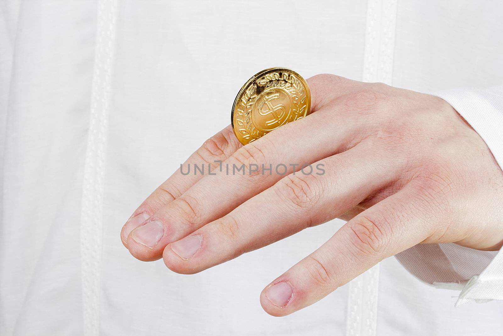 Close-up photograph of a golden coin between a man's fingers.