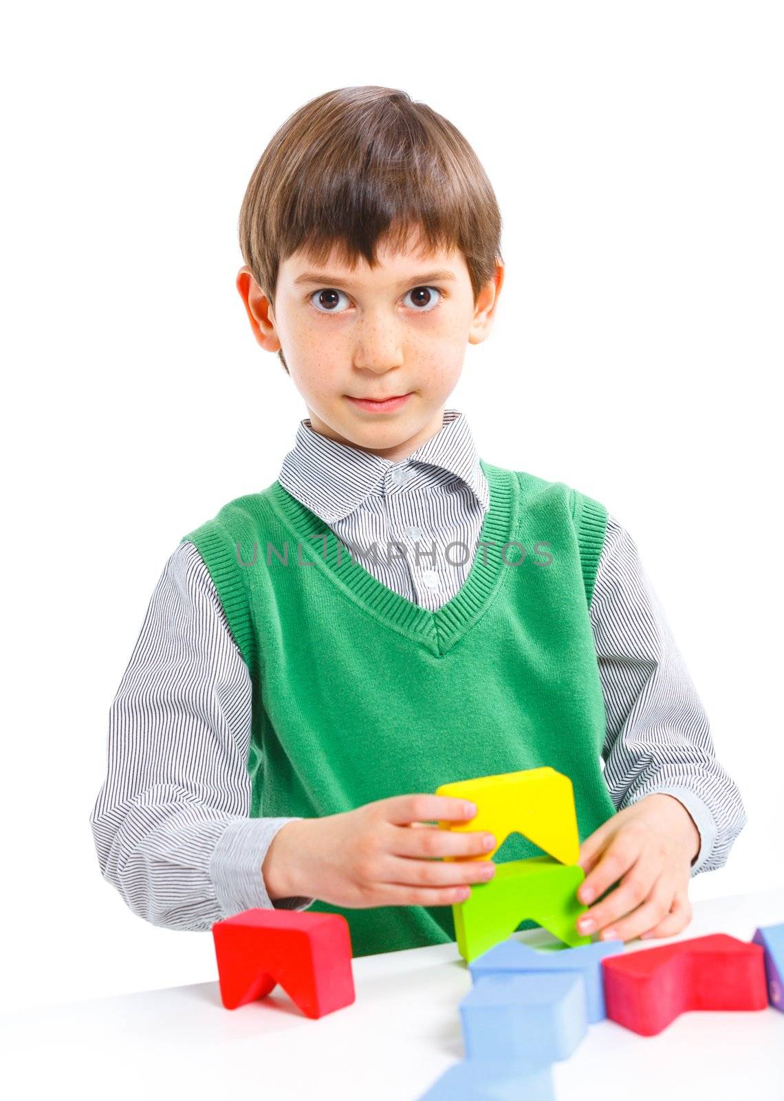 A smiling little boy is building a toy block. Isolated on white background