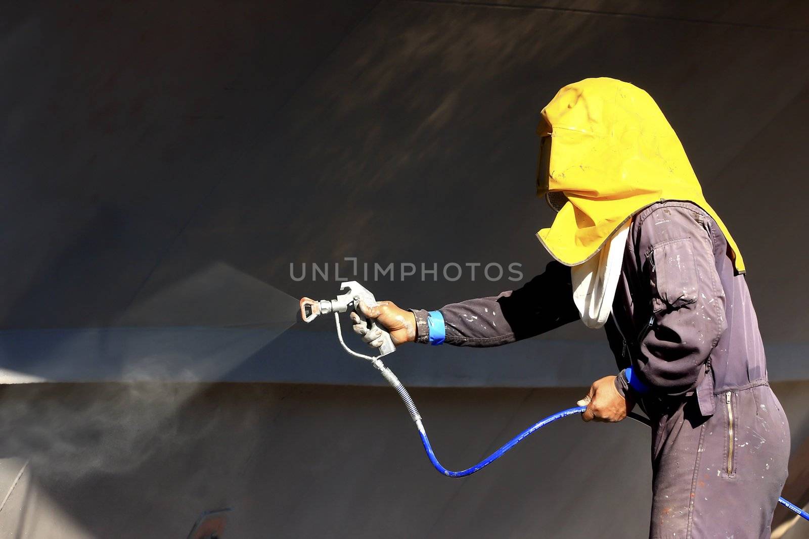 worker painting ship hull using airbrush