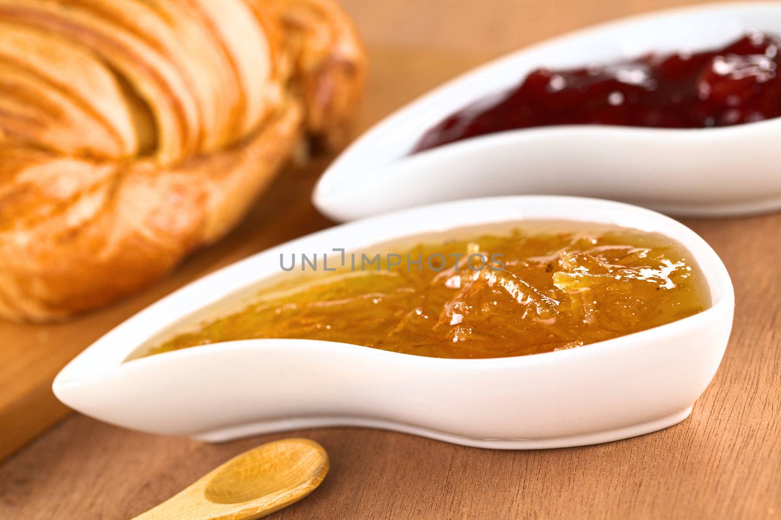 Orange and strawberry jam with croissant (Selective Focus, Focus on the front of the orange jam on the right side of the image)