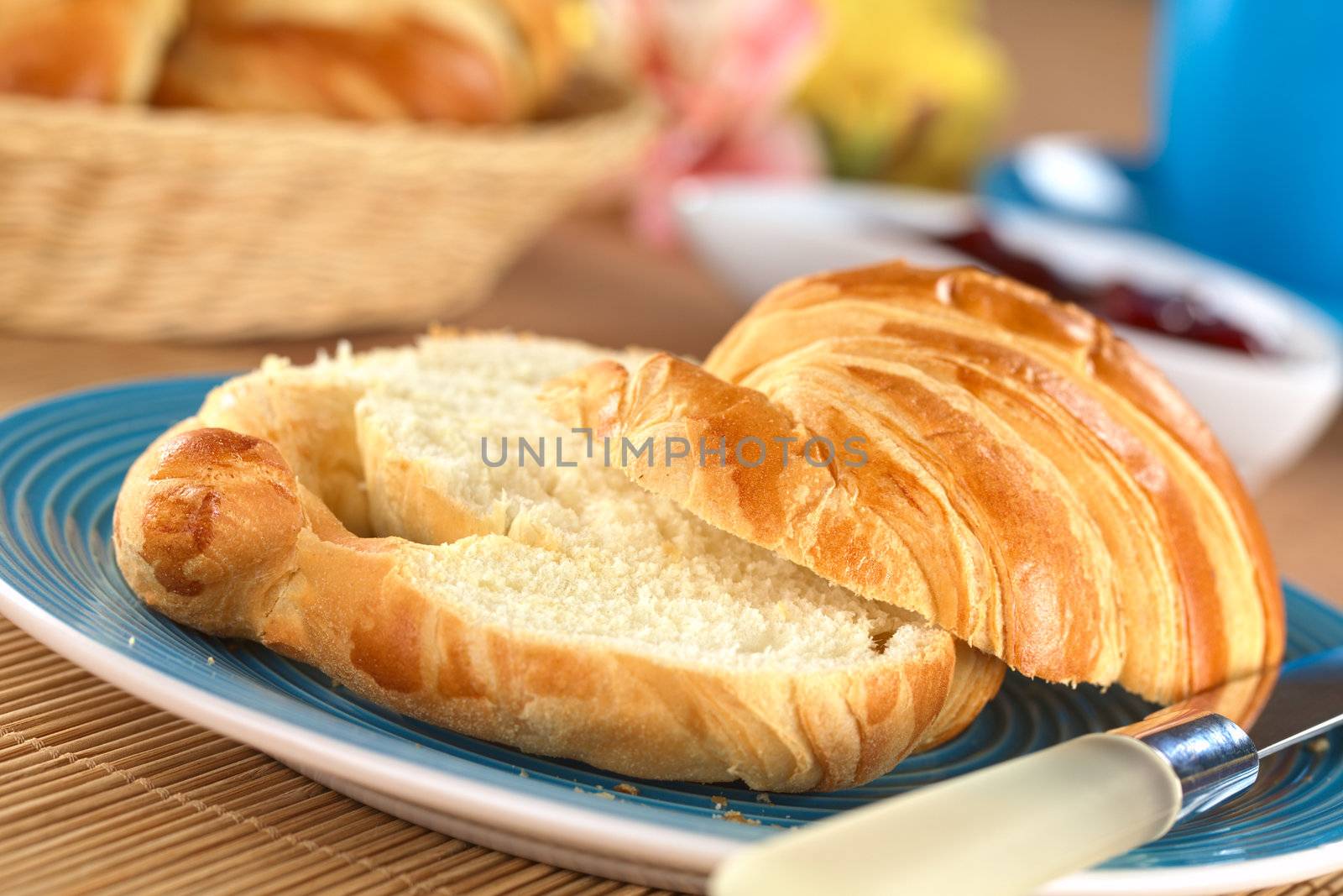 Two half croissants with strawberry jam in the back (Selective Focus, Focus on the front of the upper croissant half)