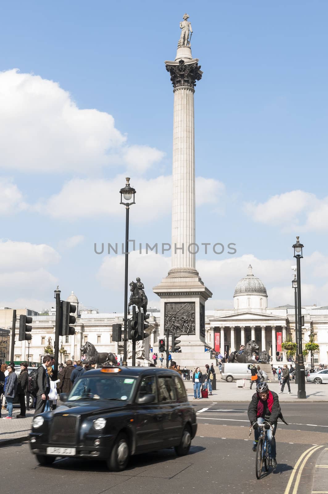 LONDON, UK - APRIL 02: Famous black cab driving by Trafalgar Square, with Nelsons Column in the background. April 02, 2012 in London.