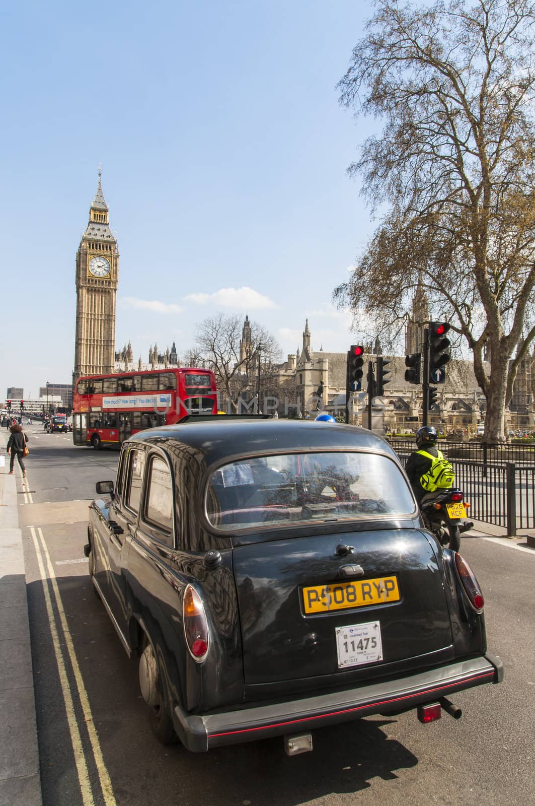 LONDON, UK - APRIL 02: Famous black cab driving by Houses of Parliament, with Big Ben prominent in the picture. April 02, 2012 in London.