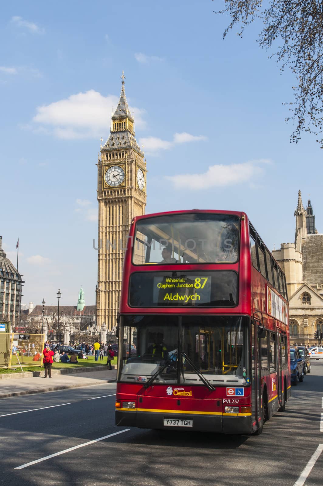 LONDON, UK - APRIL 02: Famous red double-decker bus driving by Houses of Parliament, with Big Ben prominent in the picture. April 02, 2012 in London.