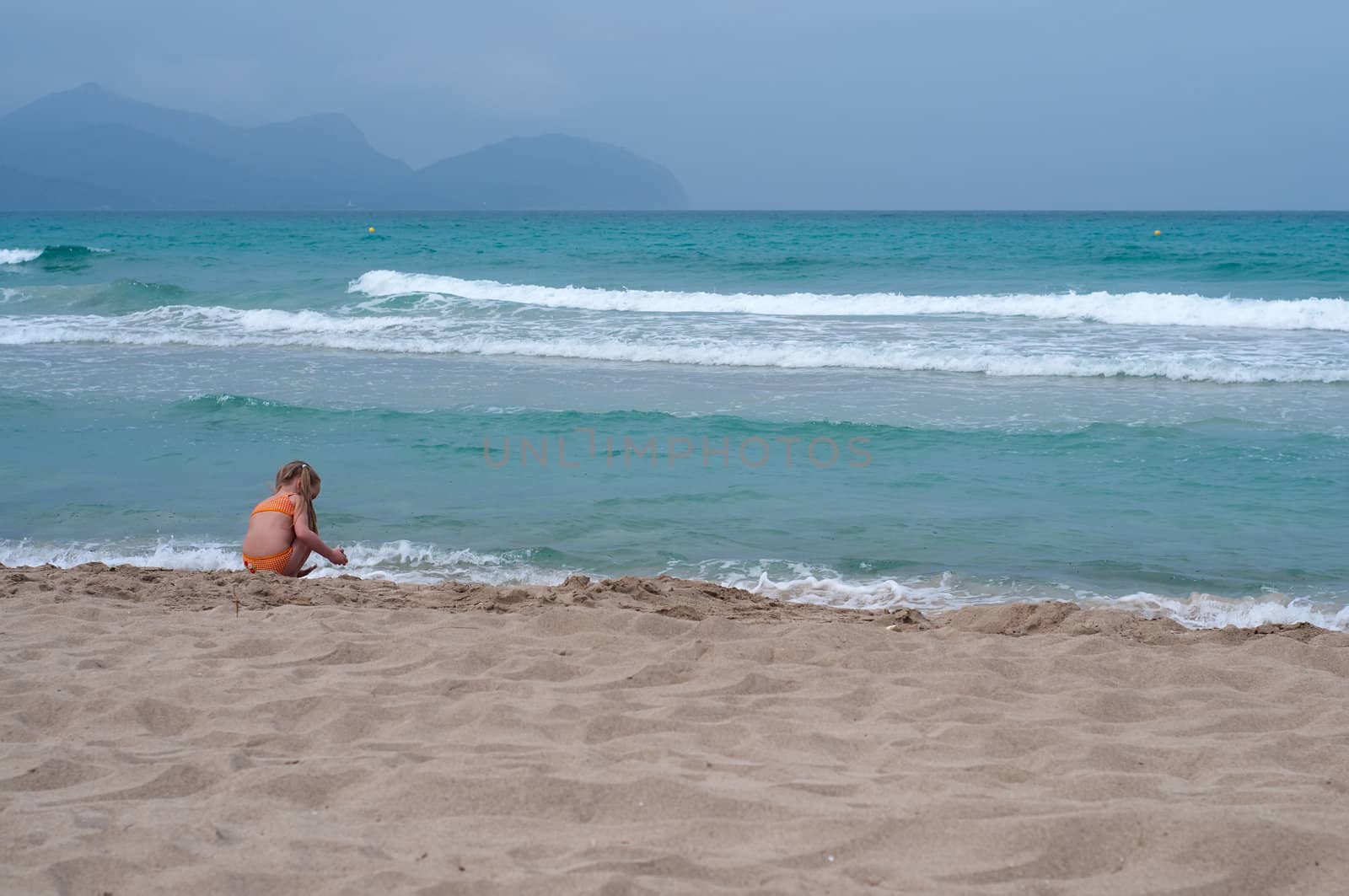 Little girl playing on the beach, sea nad sand