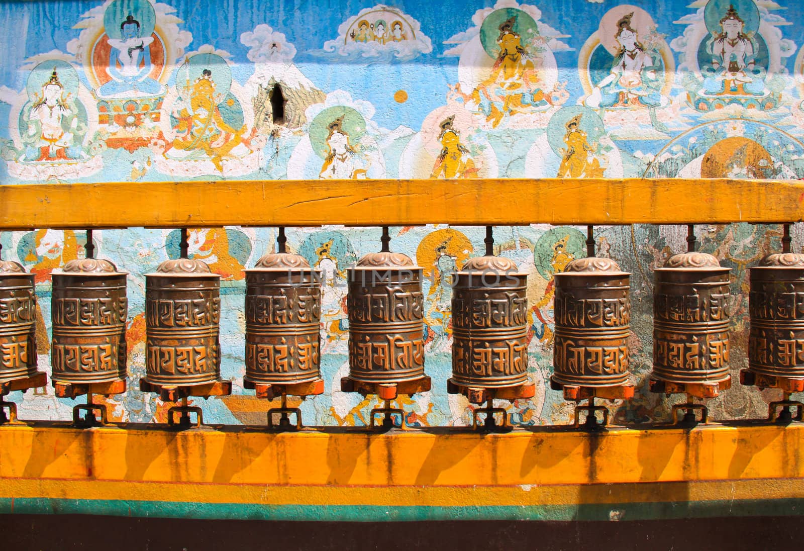 Buddhist prayer wheels with ancient art wall, Nepal