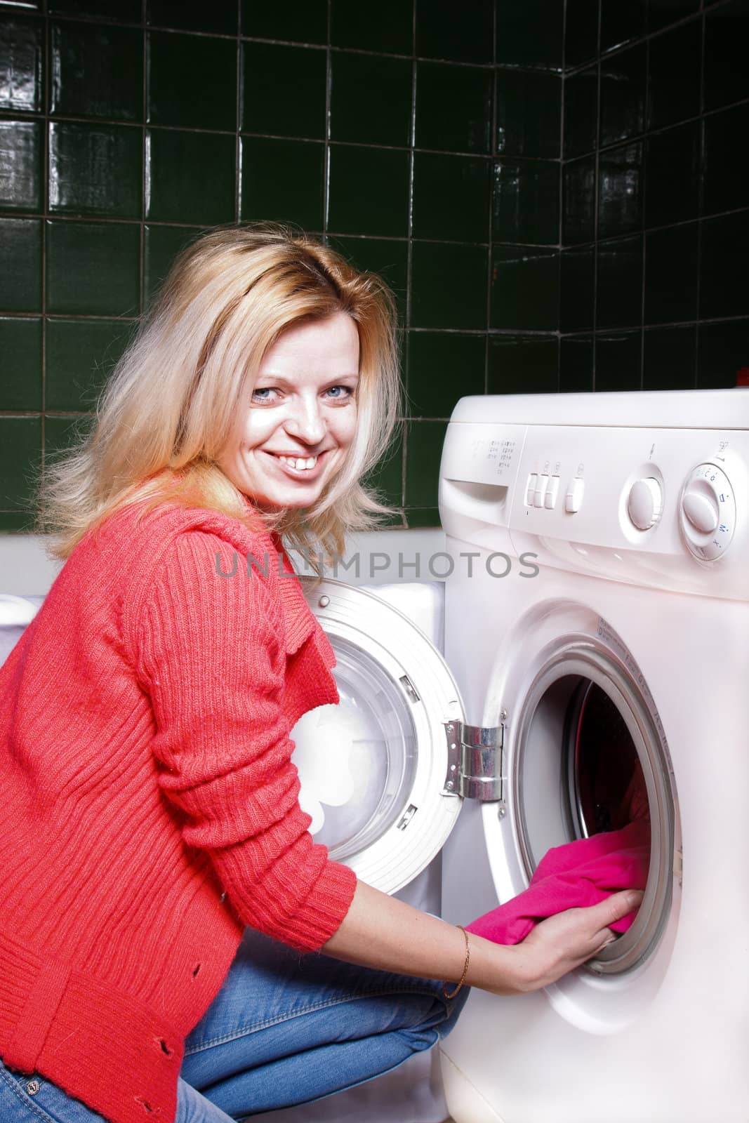smiling woman puts clothes in a washing machine