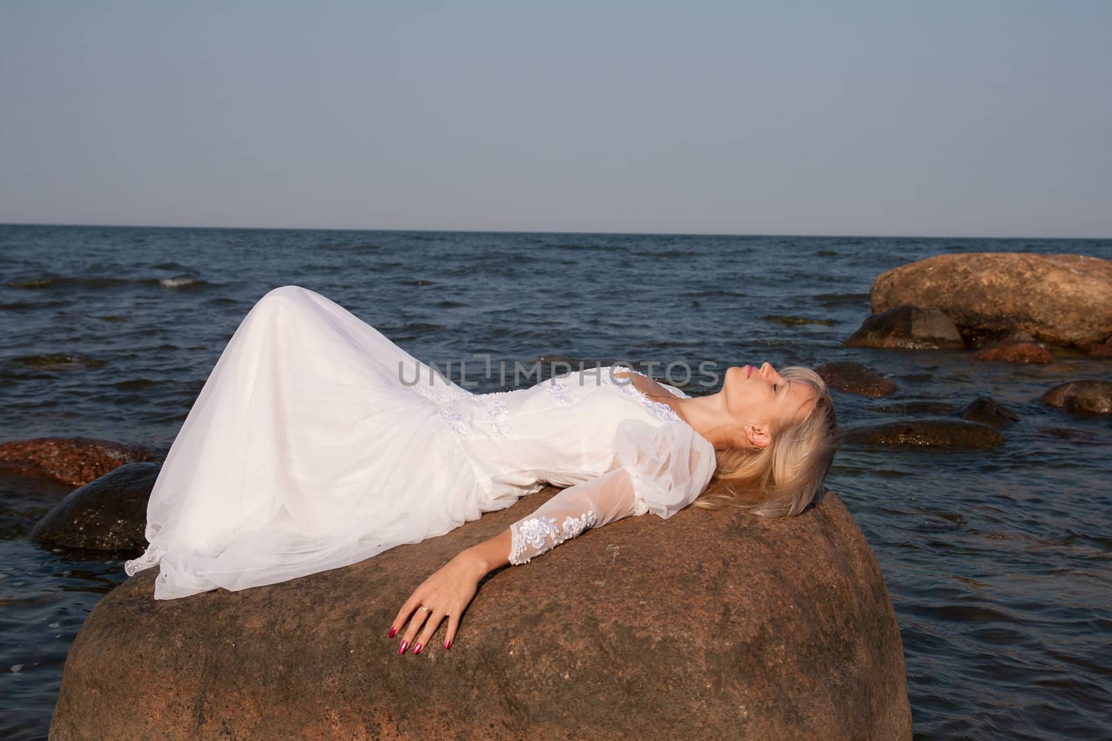 Woman lying on rock at seaside