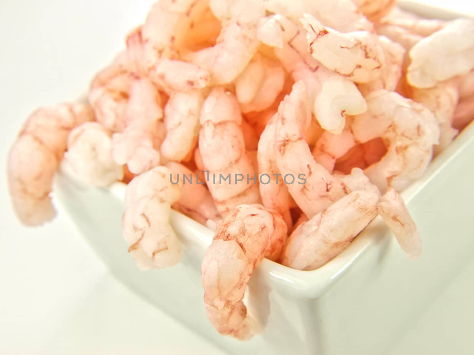 Peeled shrimps, isolated in a white bowl towards white