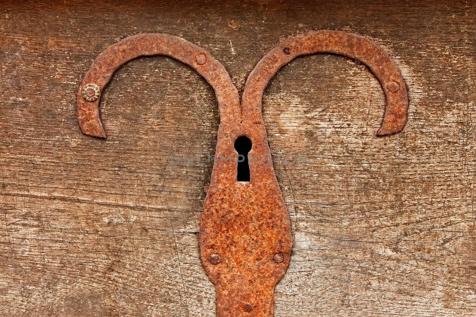 Fragment of ancient outmoded wooden chest with rusty metal plate and hole for key