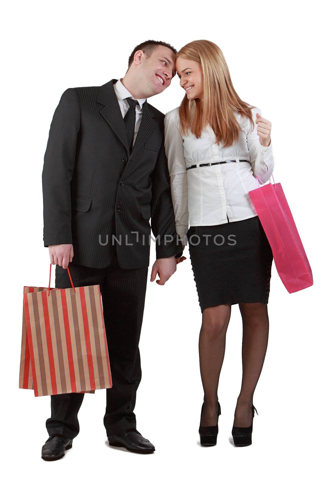 Happy young couple with shopping bags against a white background.