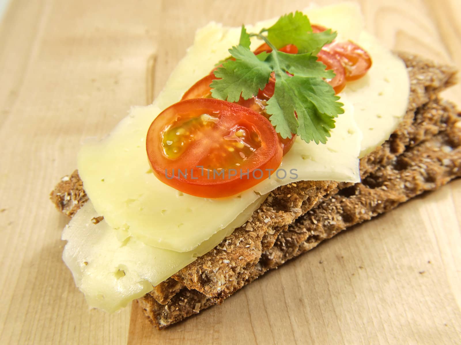 Cracker, tomato and cheese, isolated on wood