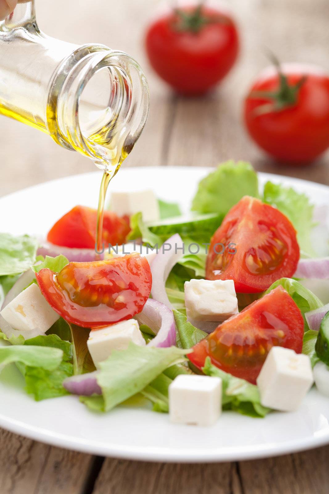 oil pouring over fresh salad 