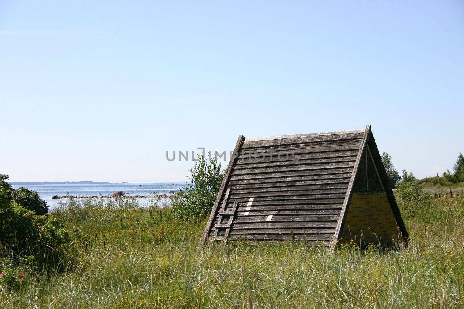 Tent at the seashore, a wooden house