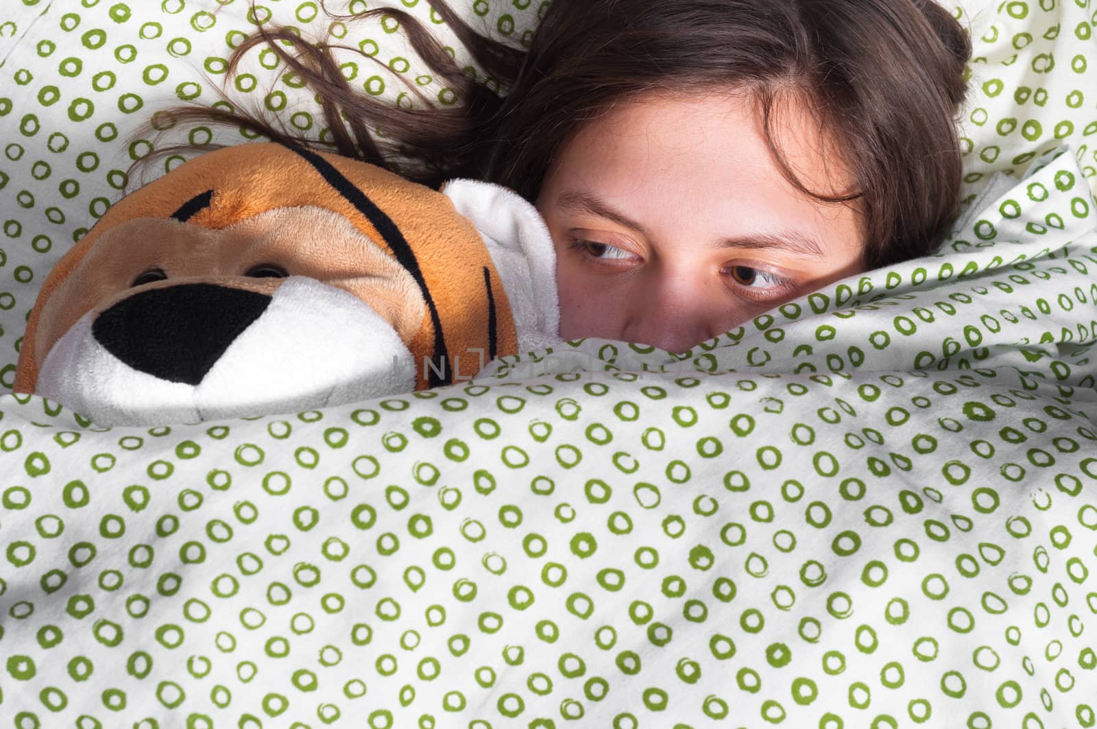 young girl in bed holding teddy bear