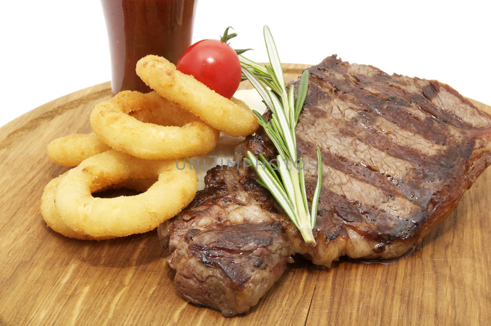 steak grilled with onion rings and sauce on a wooden plate