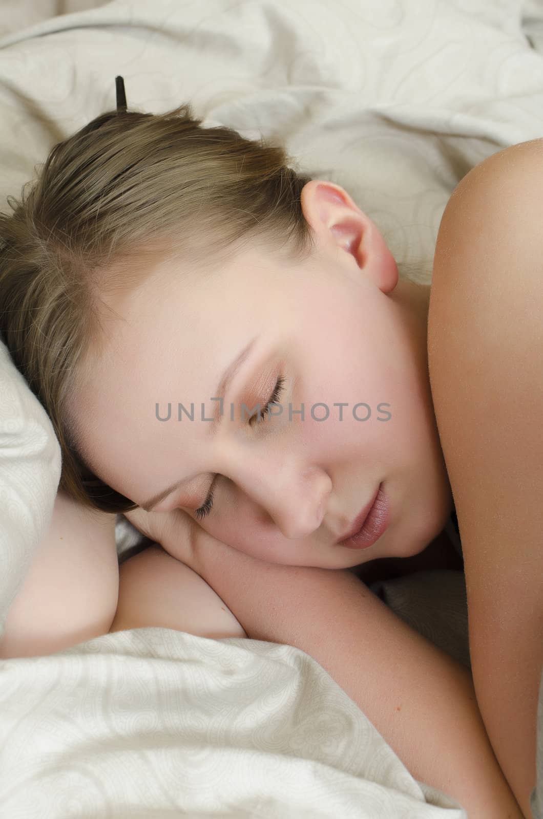Young girl sleeps in the bed under the covers