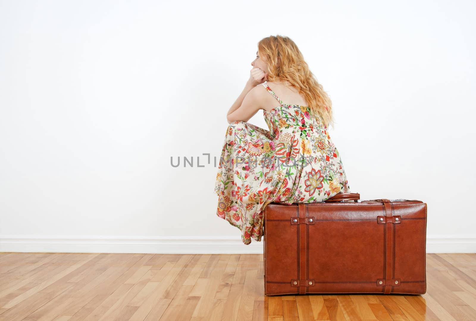 Girl sitting on a vintage suitcase anticipating travel by anikasalsera