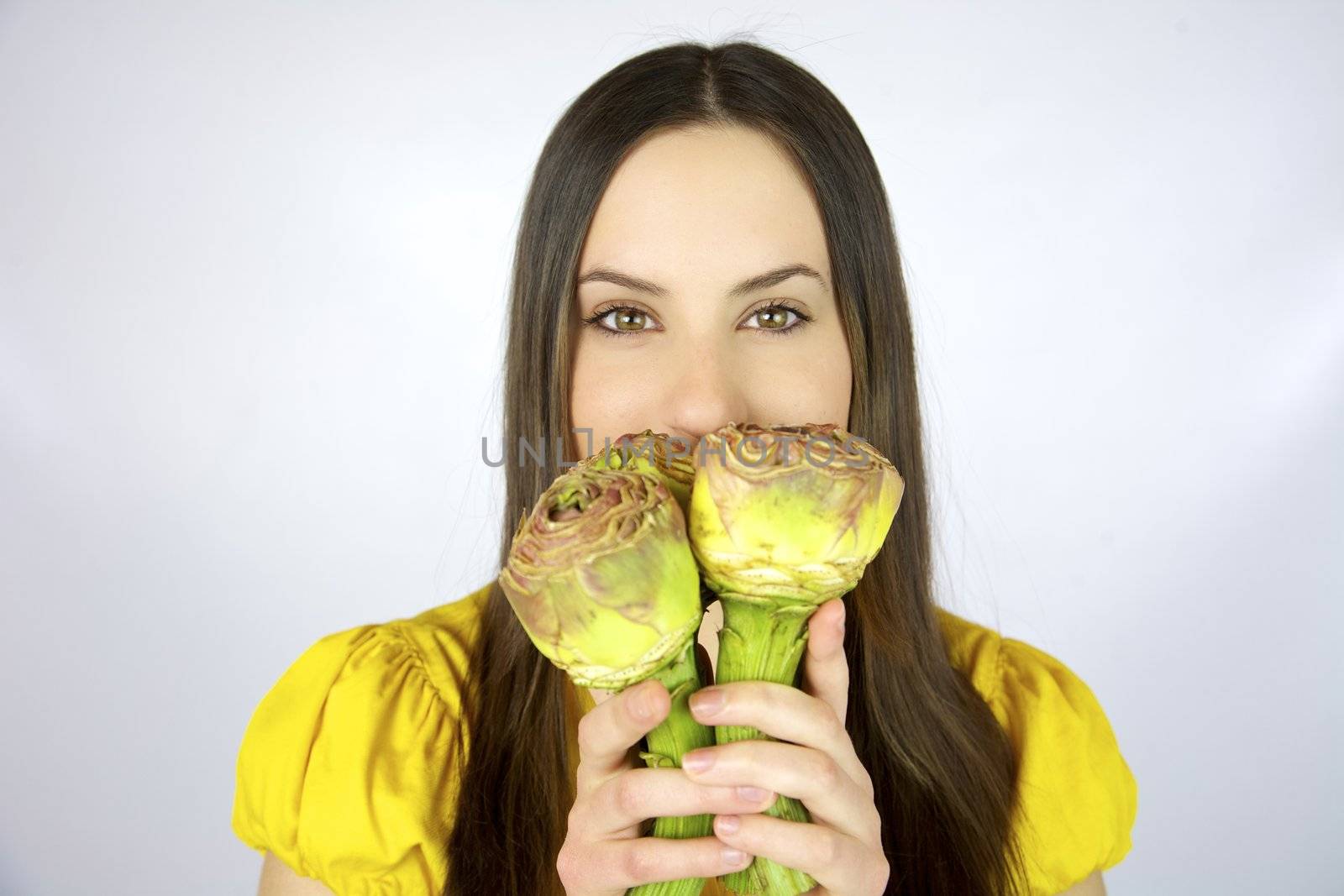Female model with artichokes in her hands and yellow shirt