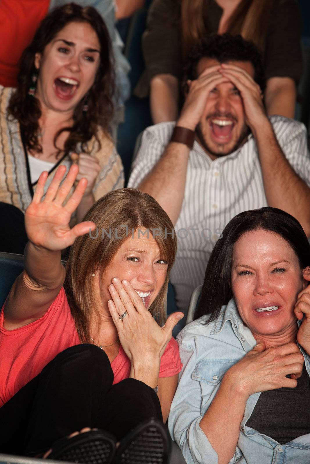 Screaming people curled up in seats at a movie theater