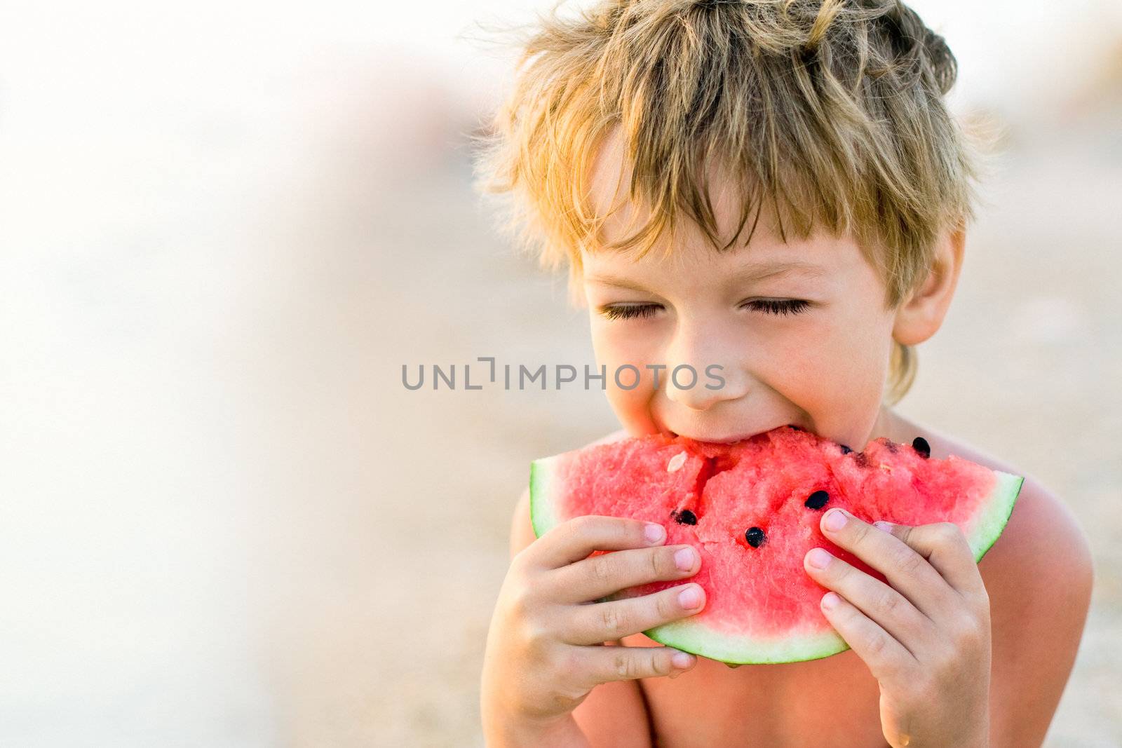 boy taking a bite of watermelon